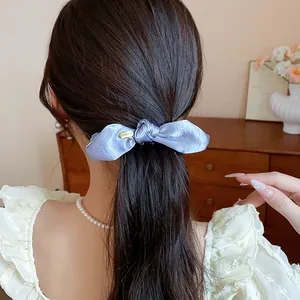 Close-up detail of an elegant light blue satin bow hair twist clip worn on a low ponytail