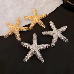 Detailed close-up of vintage starfish stud earrings with a unique pleated metallic texture.