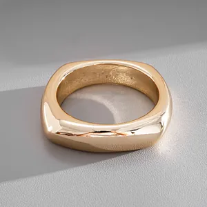 Detailed close-up of a chunky polished gold-tone square ring with a smooth finish
