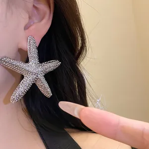 Detailed close-up of a textured oversized silver starfish stud earring on ear