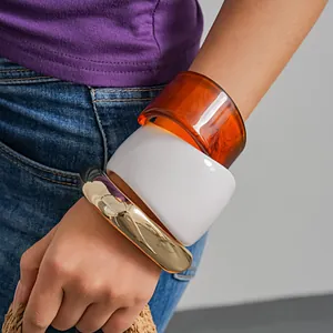 Detailed view of chunky resin bangles in amber and white with gold metallic cuff