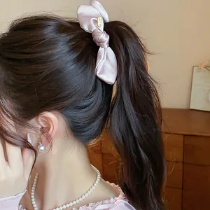 Detailed view of a pink satin bow hair clip styled on a ponytail for elegant look