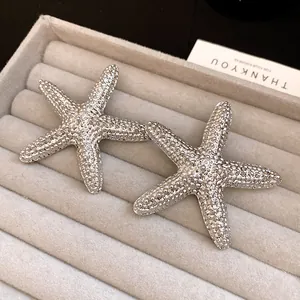Close-up detail of silver starfish stud earrings with unique wrinkled texture finish