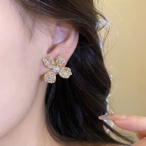Elegant gold-tone floral stud earrings with sparkling zirconia and central pearl accent
