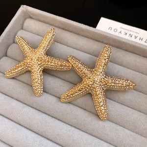 Macro view showing the intricate textured surface of golden starfish stud earrings in a tray.