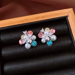 Detailed close-up of floral cluster stud earrings with colorful rhinestones and white pearls