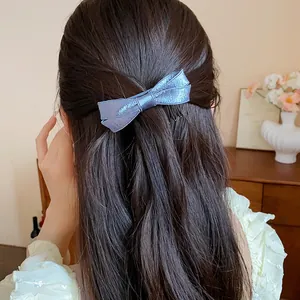Close-up of elegant blue satin bow hair clip worn by a woman with long wavy hair