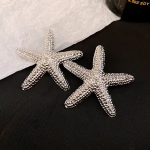 Close-up of vintage silver starfish earrings with textured beaded surface design