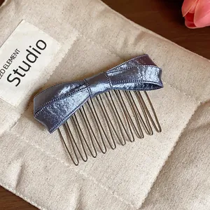 Close-up of elegant purple satin bow hair comb accessory on a beige canvas pouch