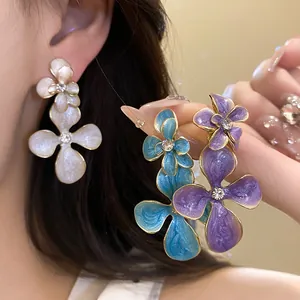Close-up of elegant enamel flower drop earrings with rhinestone centers in multiple colors