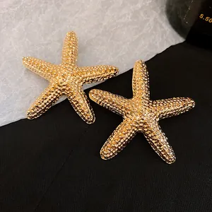 Detailed close-up showing the textured surface of gold-tone starfish stud earrings