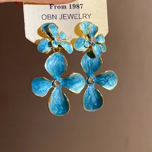 Close-up detail of vintage style blue enamel flower drop earrings with sparkling rhinestones.