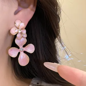 Detailed close-up of pink enamel flower drop earrings with sparkling rhinestone centers