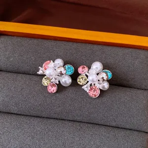 Close-up detail of colorful zircon flower cluster stud earrings with white pearls