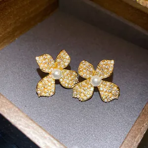 Macro view of elegant vintage gold flower earrings with inlaid pearls and zirconia