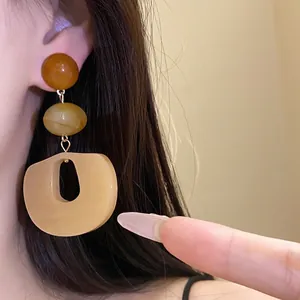 Elegant acrylic oval dangle earrings with amber beads and silver needle posts.