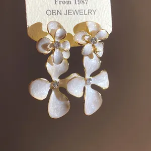 Close-up of elegant flower pendant earrings with pearl white enamel and crystal center