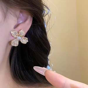 Close-up view of an elegant floral-shaped earring encrusted with zircons and a pearl on ear