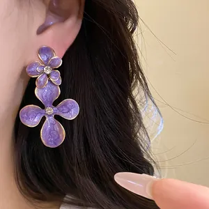 Close-up detail of vintage purple enamel flower drop earrings with rhinestones worn on ear
