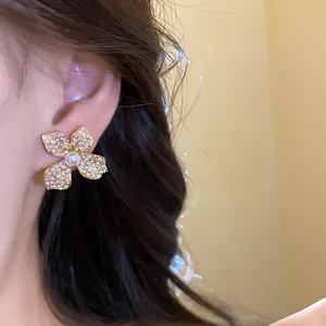 Close-up of elegant vintage flower stud earring with pearls and zircons worn on ear