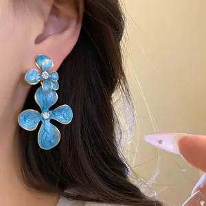 Close-up of elegant blue oil-drop flower drop earrings with sparkling rhinestone centers