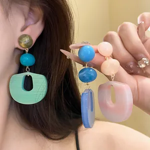 Detailed view of colorful acrylic geometric drop earrings shown on an Asian model
