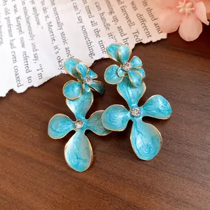 Macro view of vintage blue enamel flower earrings with sparkling rhinestone centers on wood surface