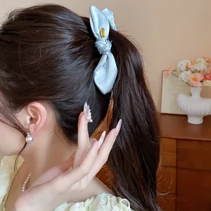 Elegant light blue satin bow hair clip shown as a detail on a brunette ponytail style