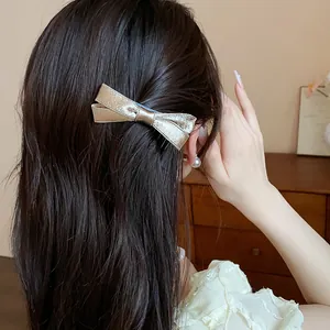 Elegant gold satin bow hair clip worn by a model showing high-end exquisite detail view.
