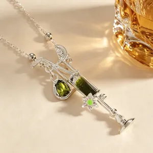 Detalle de un collar con colgante de cóctel en plata con cristales verdes esmeralda pulidos.