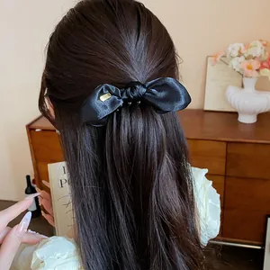 Close-up view of a black satin bow twist clip styled on long dark hair gracefully.