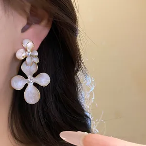 Detailed view of elegant white oil-drop flower earrings with rhinestones on model
