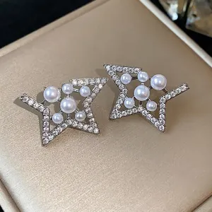 Elegant star-shaped stud earrings with pavé zirconia and assorted white pearls on gold base.