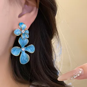 Detailed macro view of elegant blue enamel flower drop earrings with rhinestone centers