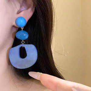 Detailed close-up showing textured blue acrylic marbled drop earring on model's ear