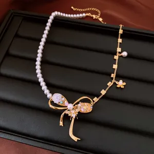 Detailed shot of a vintage gold bow necklace with pearls and zircon flower charms