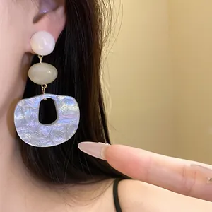 Close-up of elegant iridescent acrylic drop earring on model's ear
