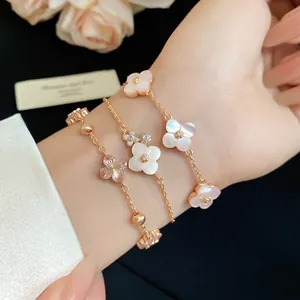 Detailed view of three pink mother-of-pearl floral bracelets on a wrist.
