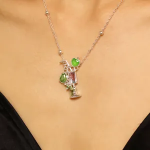Primer plano de collar con colgante de cóctel plateado con piedras verdes y rosas