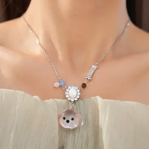 Primo piano di una graziosa collana con testa di cane in resina rosa e osso di zircone