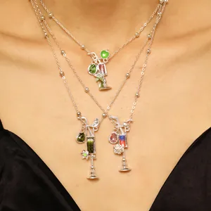 Detalle de tres collares superpuestos con colgantes en forma de cóctel de plata