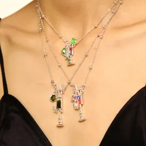 Primer plano de tres collares con temática de cóctel y piedras de colores en el cuello de una modelo