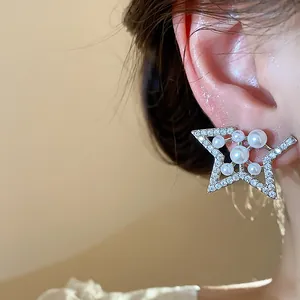 Close-up detail of star-shaped zircon and pearl stud earrings elegantly worn on ear