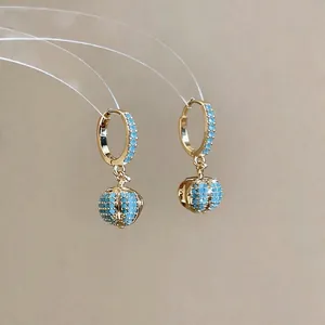 Elegant 18k gold plated hoop earrings with shimmering blue zircon sphere charms on beige background