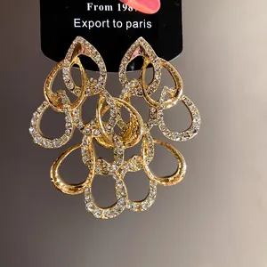 Detailed view of ornate gold teardrop earrings with shimmering crystal rhinestones set.