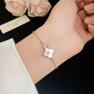 Close-up of a rose gold bracelet with shell flower and zircon accents worn on a wrist