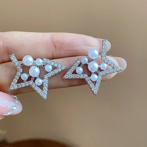 Close-up of silver star earrings featuring sparkling zircons and elegant white pearls.