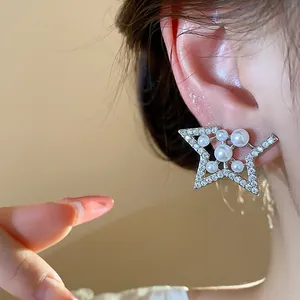 Elegant star-shaped stud earrings with pearls and zircons shown as a close-up detail on ear