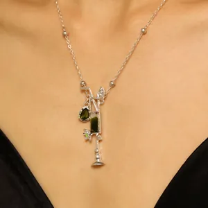 Primer plano de un collar de plata con colgante de cóctel y cristal verde