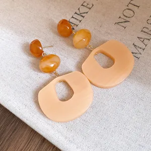 Detail of acrylic dangle earrings with amber beads and apricot oval pendants